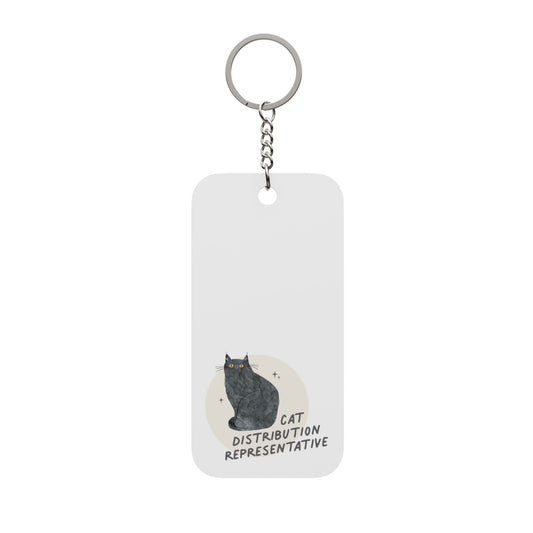 A rectangular white acrylic keychain with a silver metal split ring and chain. The keychain features a printed graphic of a black cat sitting in front of a beige circle, with the text 'CAT DISTRIBUTION REPRESENTATIVE' written below.