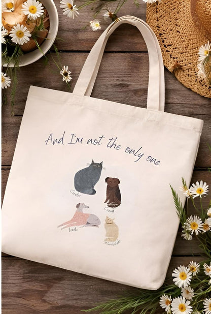 Tote bag with animal illustrations and text on a wooden surface with flowers.