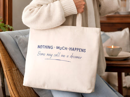 Person holding a tote bag with text in a cozy indoor setting